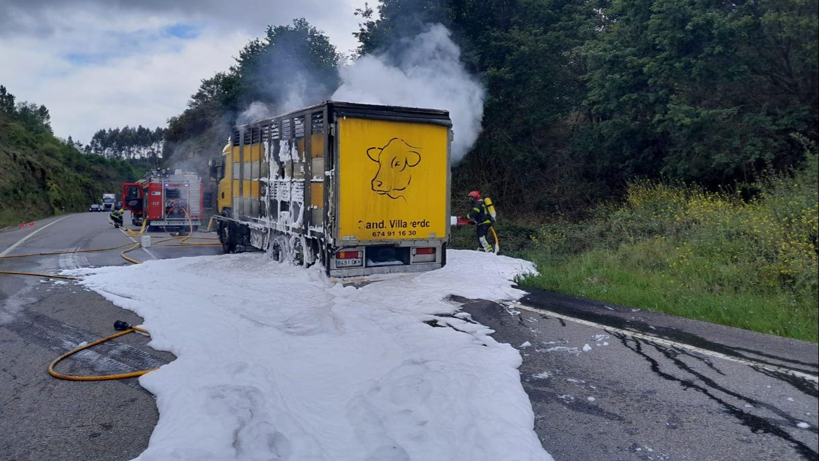 Bomberos sofocando el incendio del camión en la N-541 tras el reventón de una rueda.