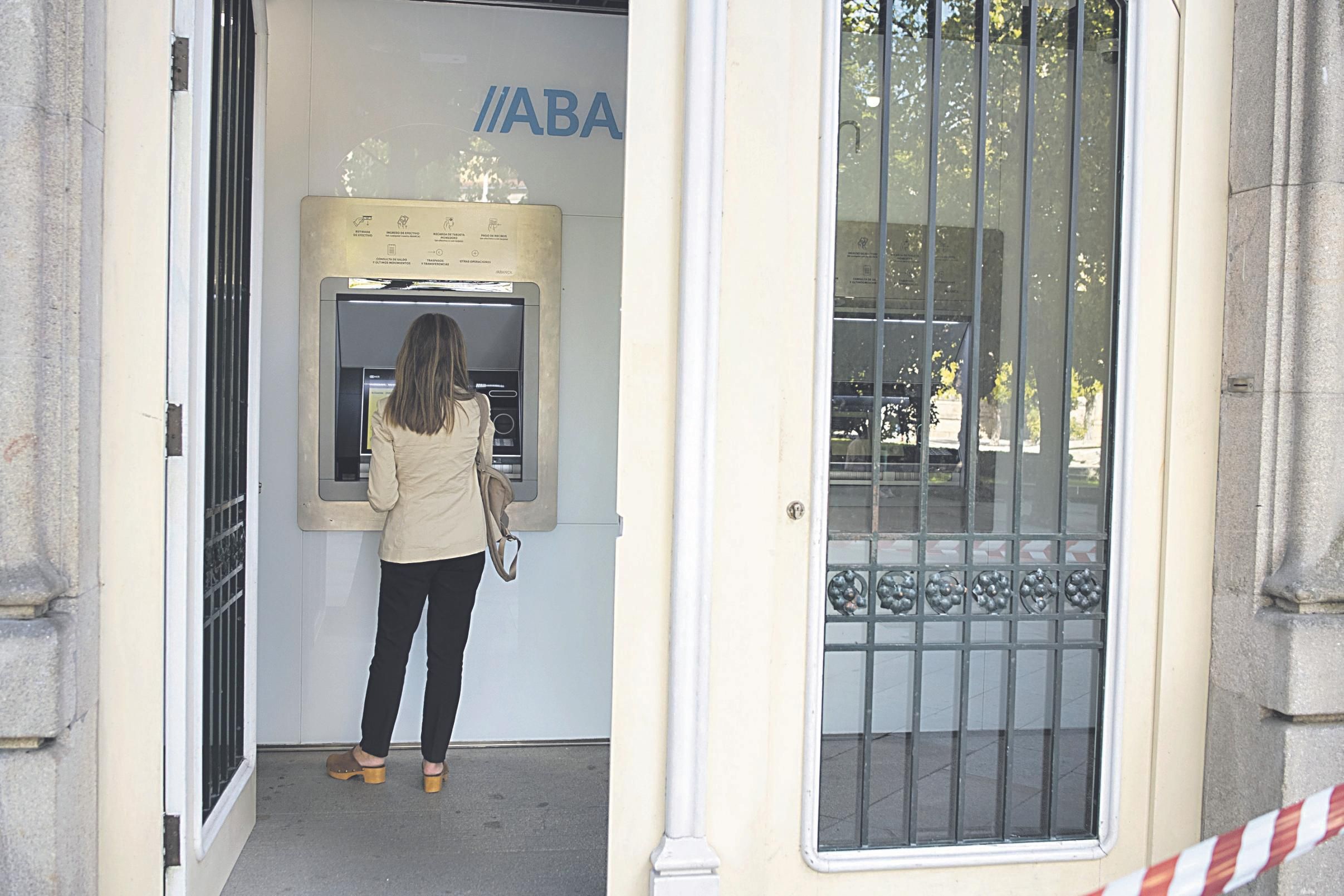 Una clienta hace una operación bancaria en un cajero de Abanca. (XESÚS FARIÑAS)