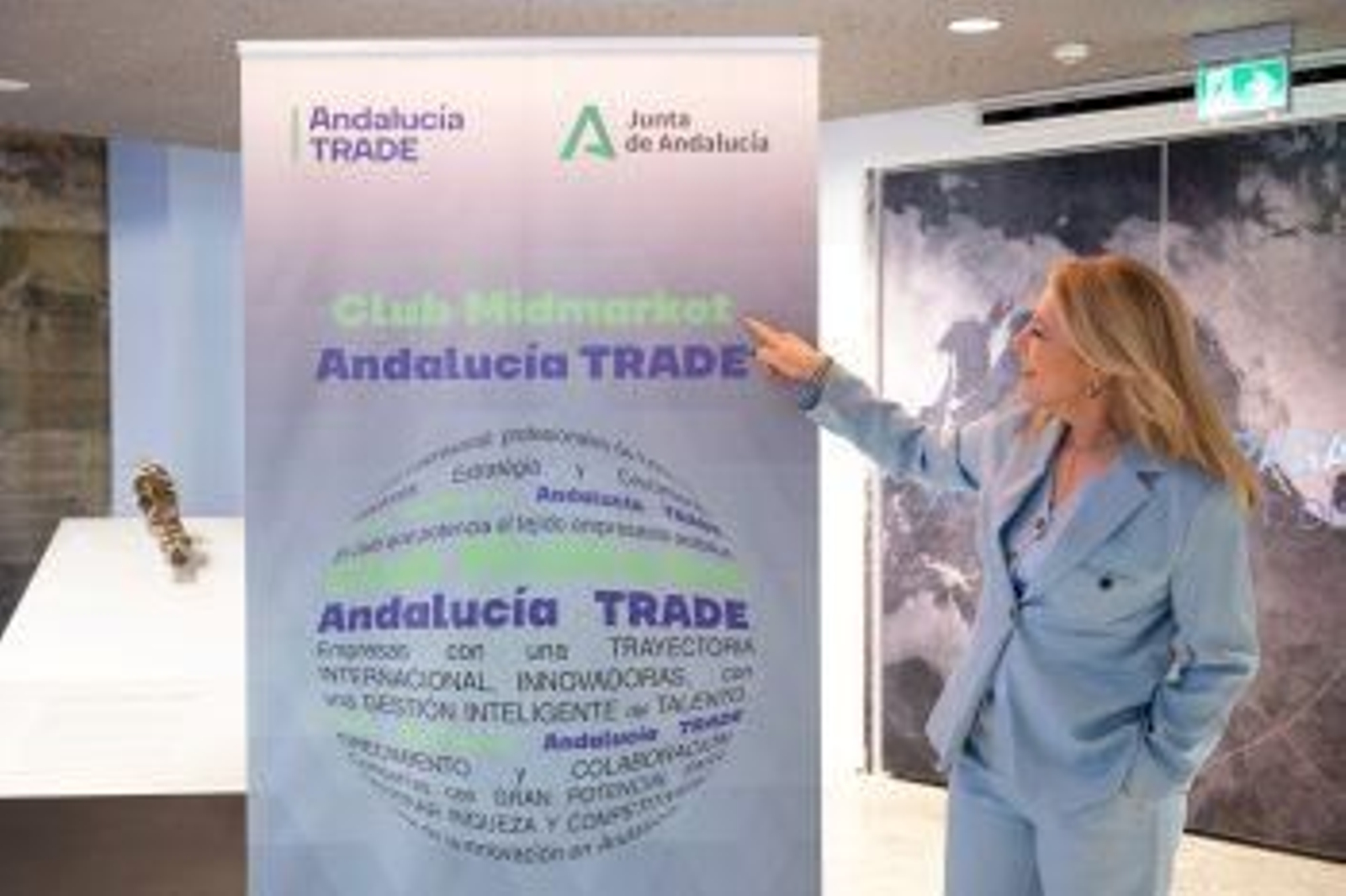 En la imagen, una mujer frente a un cartel de Andalucía Trade