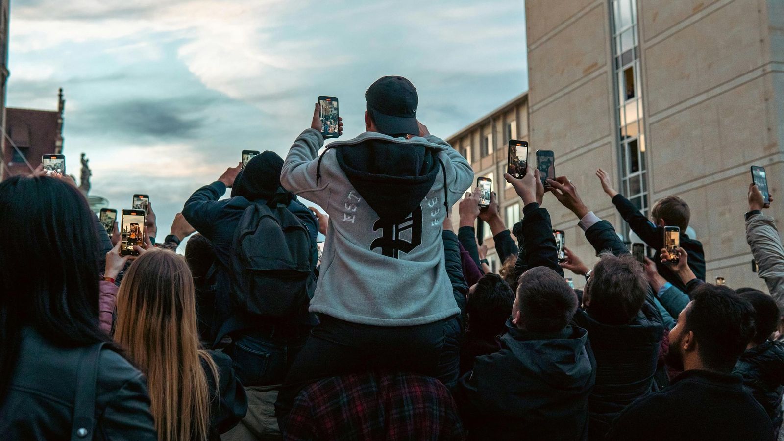 Jóvenes viendo un evento a través de sus móviles.