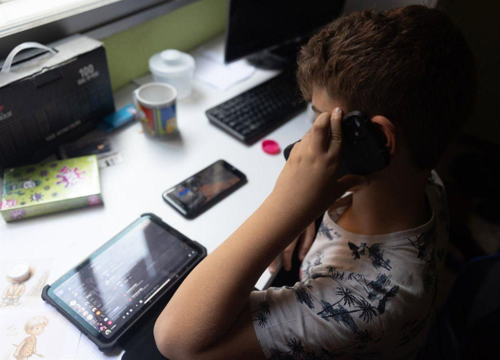 Un niño usa un teléfono móvil y una tablet.