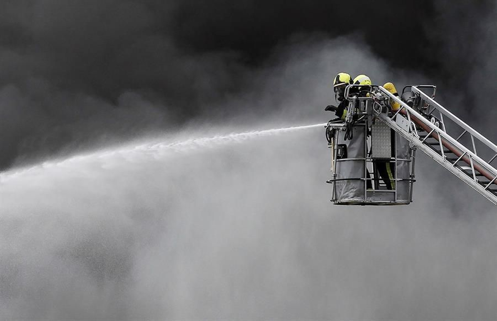 Varios bomberos intentan controlar las llamas de un incendio en el parque empresarial de O Ceao, este domingo. El secretario general del Confederación de Empresarios de Lugo (CEL), Jaime López, ha calificado este domingo como "un día negro para Lugo" por el incendio que ha calcinado al menos cuatro naves en el polígono industrial de O Ceao y que ha obligado a activar el nivel 1 del plan de emergencias de Galicia, aunque no ha provocado daños personales. EFE/Eliseo Trigo