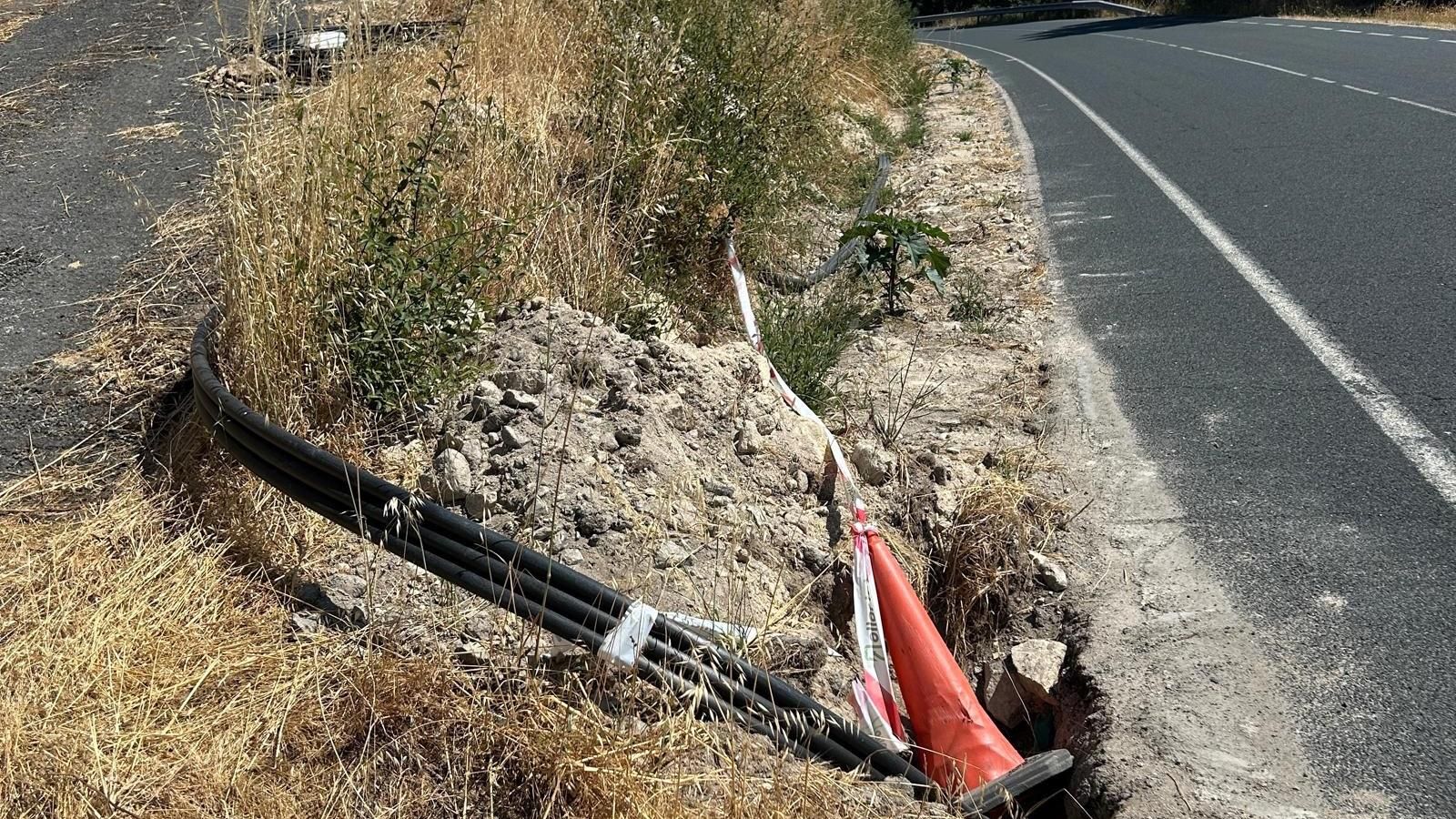 Mientras no se soterran, los cables permanecen en el suelo de cunetas y vías.