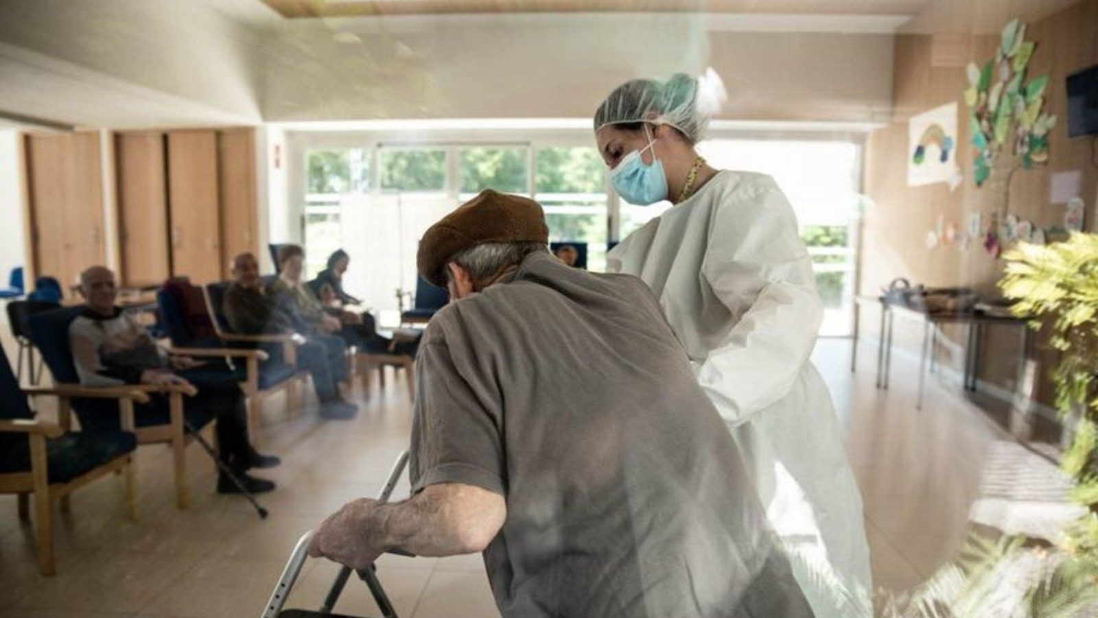 Una trabajadora del centro de mayores de Luintra ayuda a incorporarse a un usuario. (Foto: Óscar Pinal)