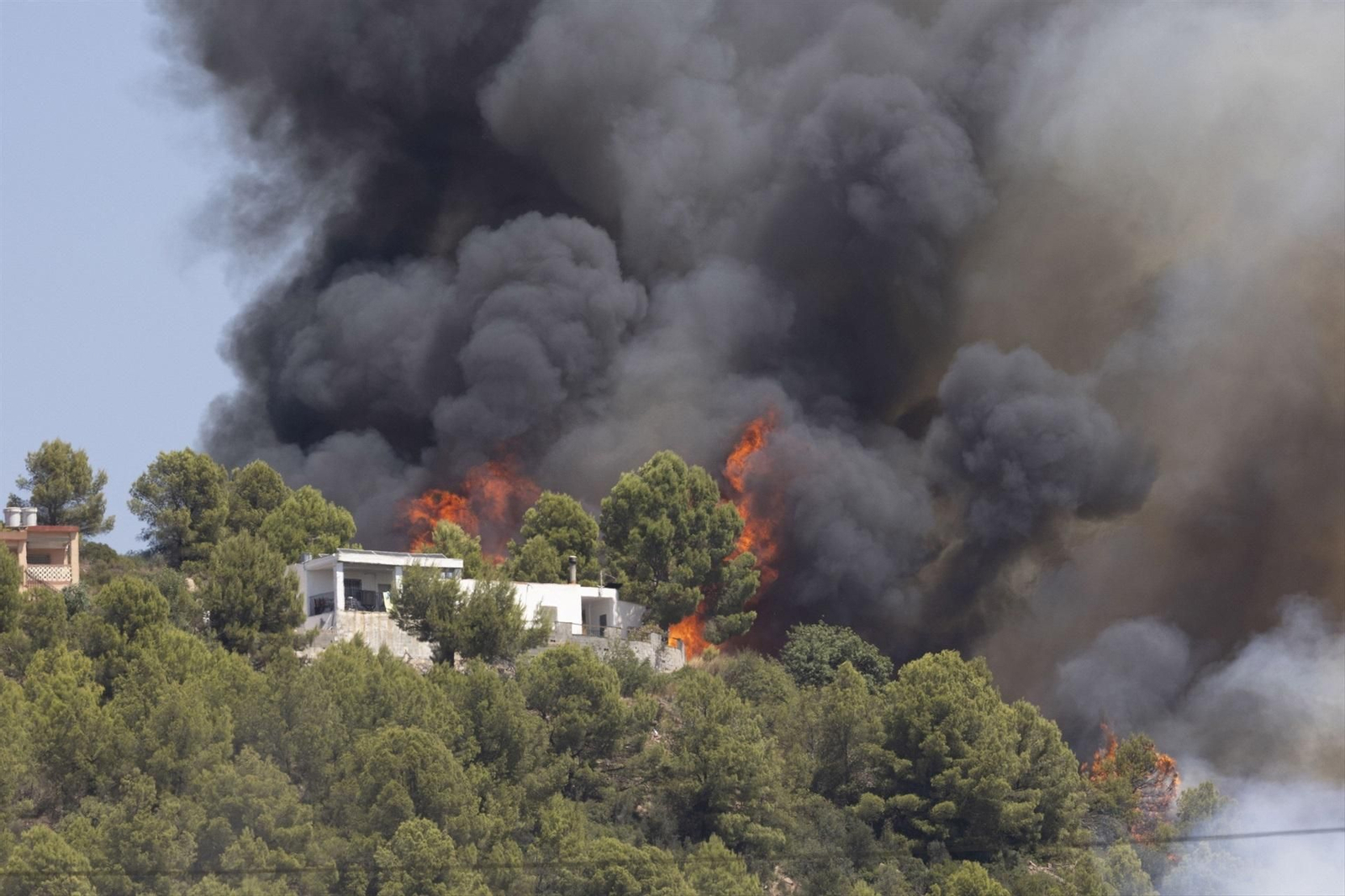 Llamas se acercan a una casa a causa de un incendio forestal, a 25 de julio de 2026, en Vall d'Uixó (Castellón)