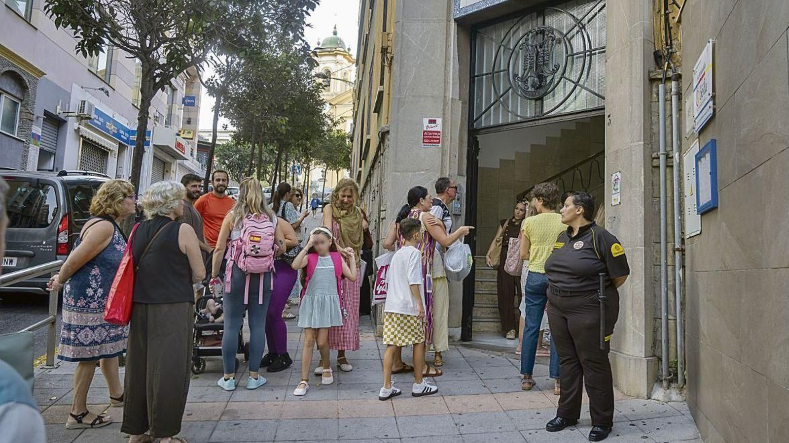 Un grupo de niños a la entrada del colegio, con seguridad privada en la puerta.