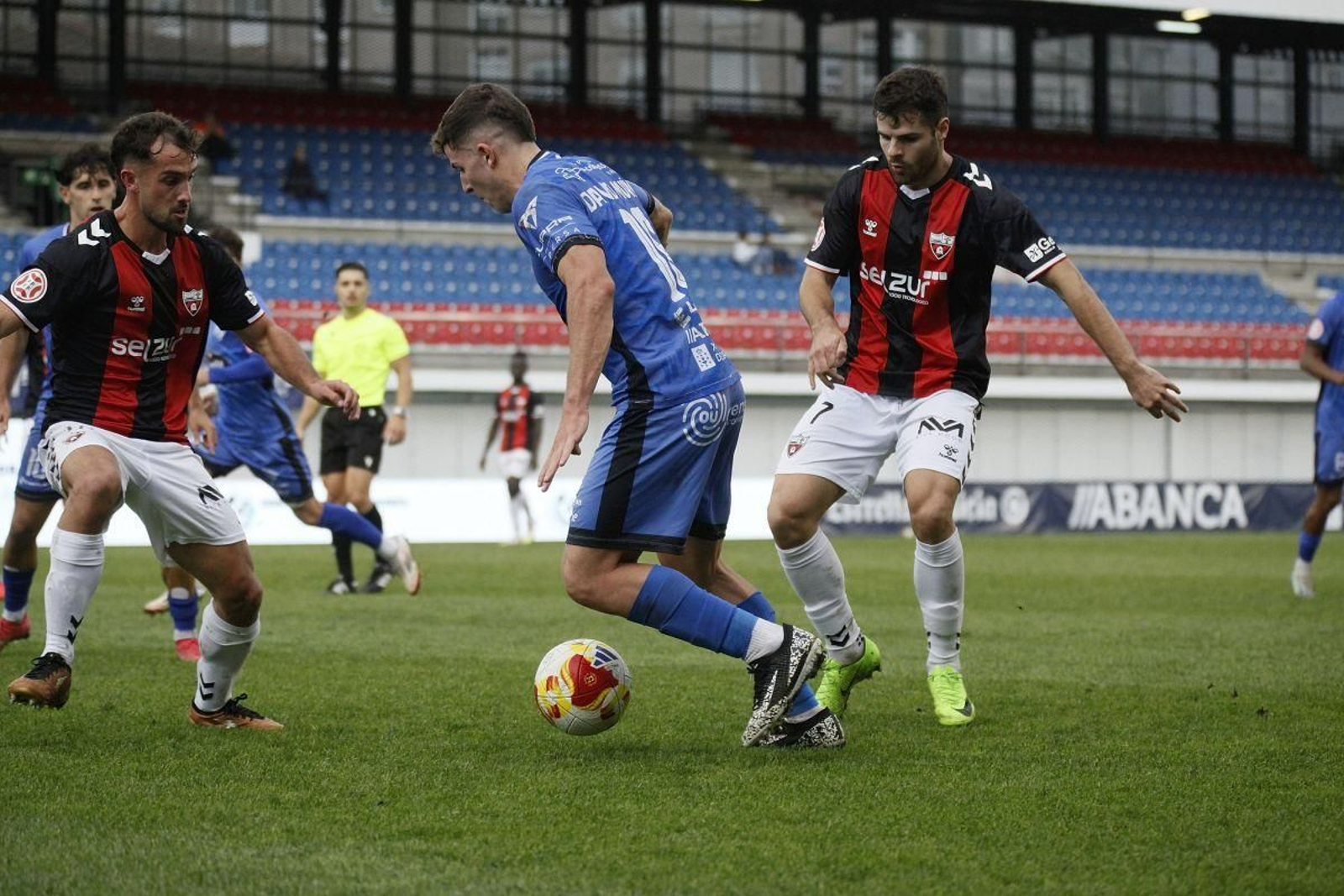 David Muñoz, centrocampista del Ourense CF, intenta superar a dos jugadores del Arenas de Getxo.