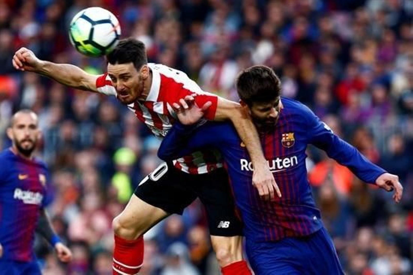 El delantero del Athletic de Bilbao, Aritz Aduriz, intenta un remate ante el defensa del FC Barcelona, Gerard Piqué.
