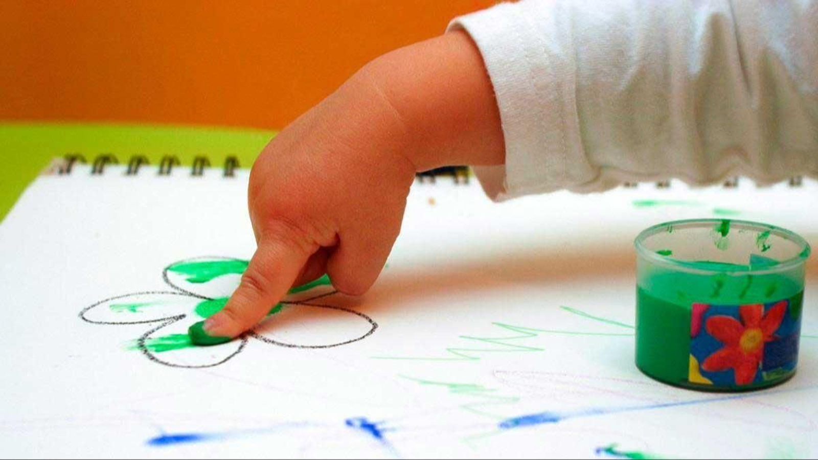 Un niño pinta un dibujo con su dedo.