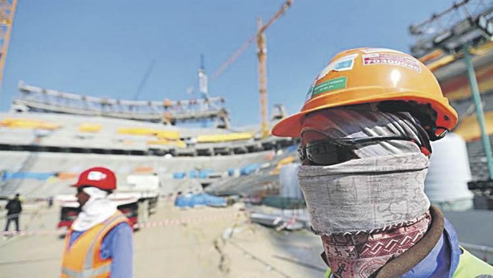 Trabajadores protegidos contra el sol en la construcción de los estadios de Qatar.