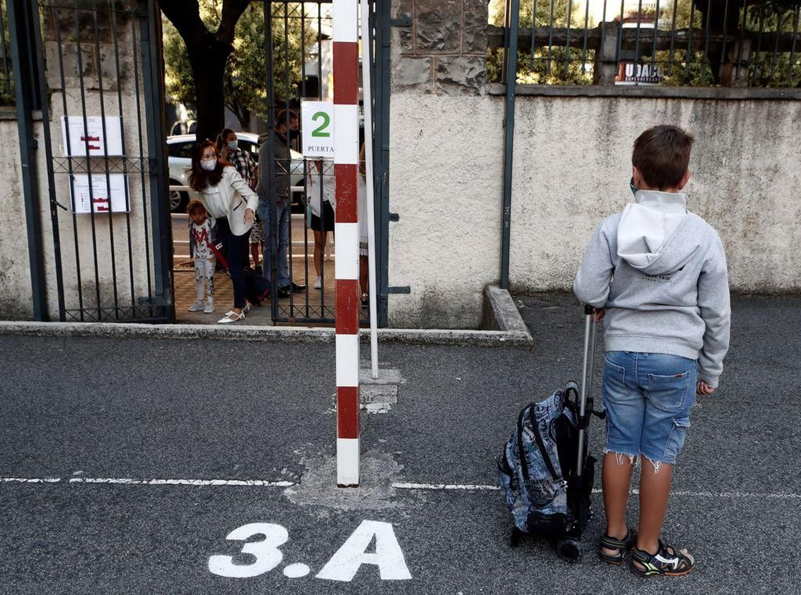 Un niño espera con mochila y mascarilla en la puerta de un colegio en Navarra.