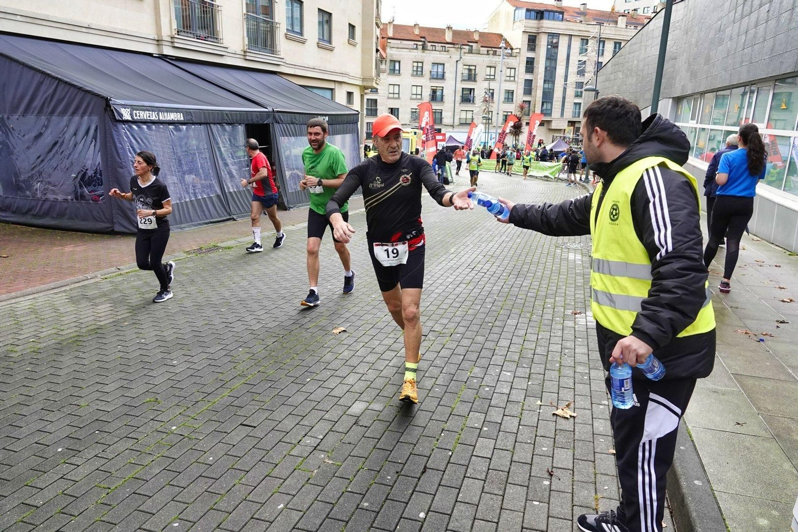 Un corredor coge agua en la Vigo+11 en Coia.