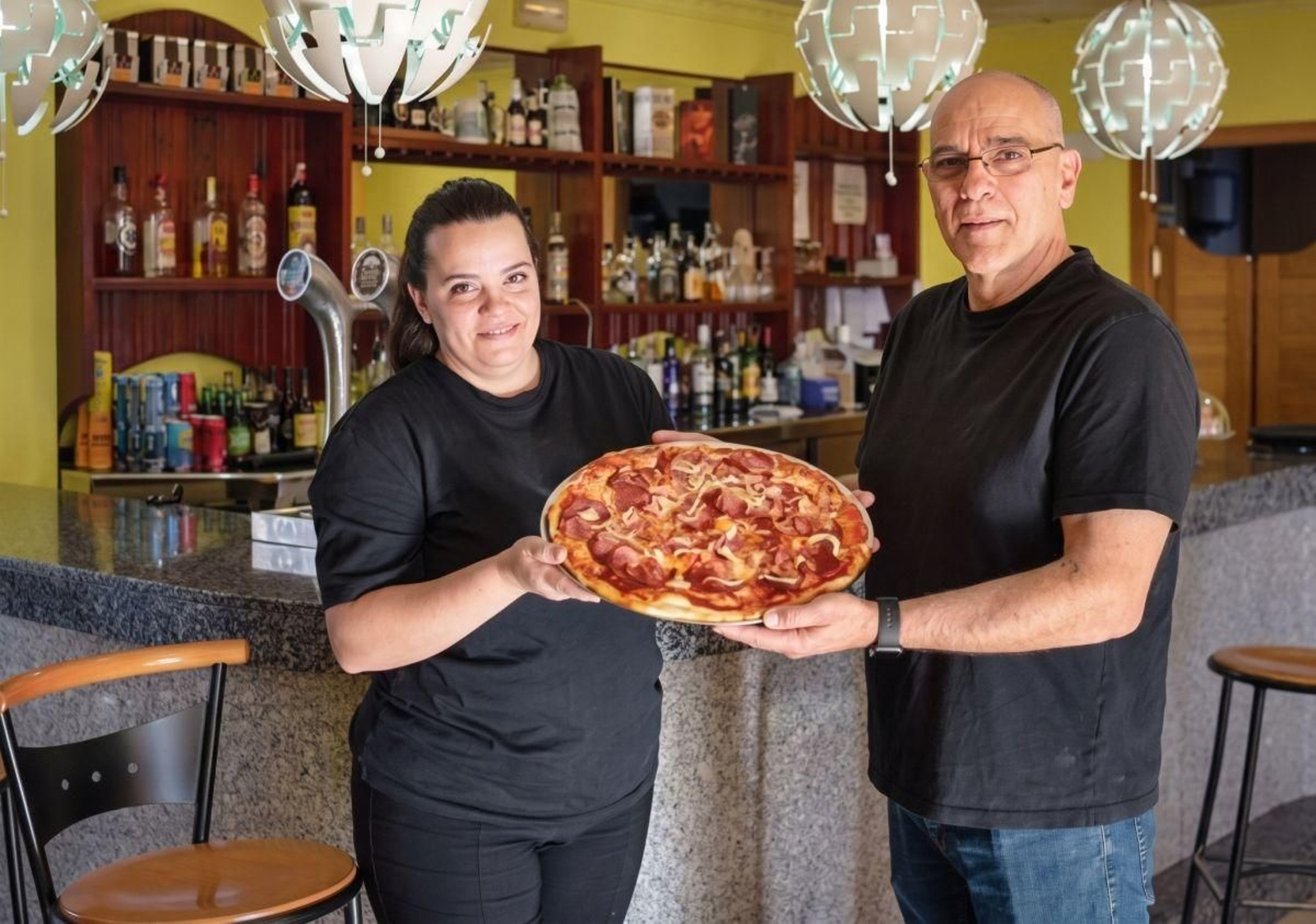 Disfrutar del verano es también entregarse a los placeres de la buena mesa sin prisas, y una buena pizza siempre tiene espacio en las reuniones familiares y cenas con amigos, especialmente cuando puede disfrutarse en rincones espectaculares donde la tradición italiana, los toques argentinos y la esencia gallega se fusionan de manera única.  Para empezar la ruta con un auténtico viaje sensorial, La Tarraza da Paolo (Ourense) destaca por sus pizzas artesanales elaboradas con ingredientes que trasladan a los comensales directamente a Italia. Su experiencia se completa con un variado surtido de antipasti y productos selectos, ideales para una cena fresca de verano.  Si buscamos un pedazo de historia y ese toque de toda la vida, Pizza Bonna (Carballiño), lleva más de 25 años enamorando a sus clientes. Preparan su masa diariamente y son el lugar idóneo para sentirse como en casa o, para quienes estén en Ourense ciudad, aprovechar su punto de “take away” en la calle Antonio Puga.  La fusión cultural también tiene su espacio este verano. En Dolce Vitta (Ourense) han logrado el equilibrio perfecto al mantener la esencia de la auténtica pizza napolitana, combinando la tradición italiana y las masas de fermentación lenta con un toque único: su alma gallega. El resultado es un producto honesto, cercano y repleto de sabor.  Por otro lado, apetece un plan más dinámico y con aire internacional, el Bar Dero (Castro Caldelas) es uno de los dinamizadores de la pizza en esta comarca. Su gran reclamo son las pizzas caseras al estilo argentino, que además puedes diseñar a tu propio gusto. Es un local perfecto para el ocio veraniego gracias a su oferta de hamburguesas artesanales, más de 30 tipos de cervezas, futbolín, billar y máquinas arcade.  Y aunque la pizza sea la reina, el verano también pide pausas matutinas y buenas charlas. El Café Bar Bellomonte - Los Cubanos (Outomuro, Cartelle) es una parada obligatoria. Este acogedor negocio familiar ofrece el rincón ideal para disfrutar de pizzas caseras con ingredientes al gusto del cliente, mientras se descansa en un entorno natural saboreando el mejor queso fundido.