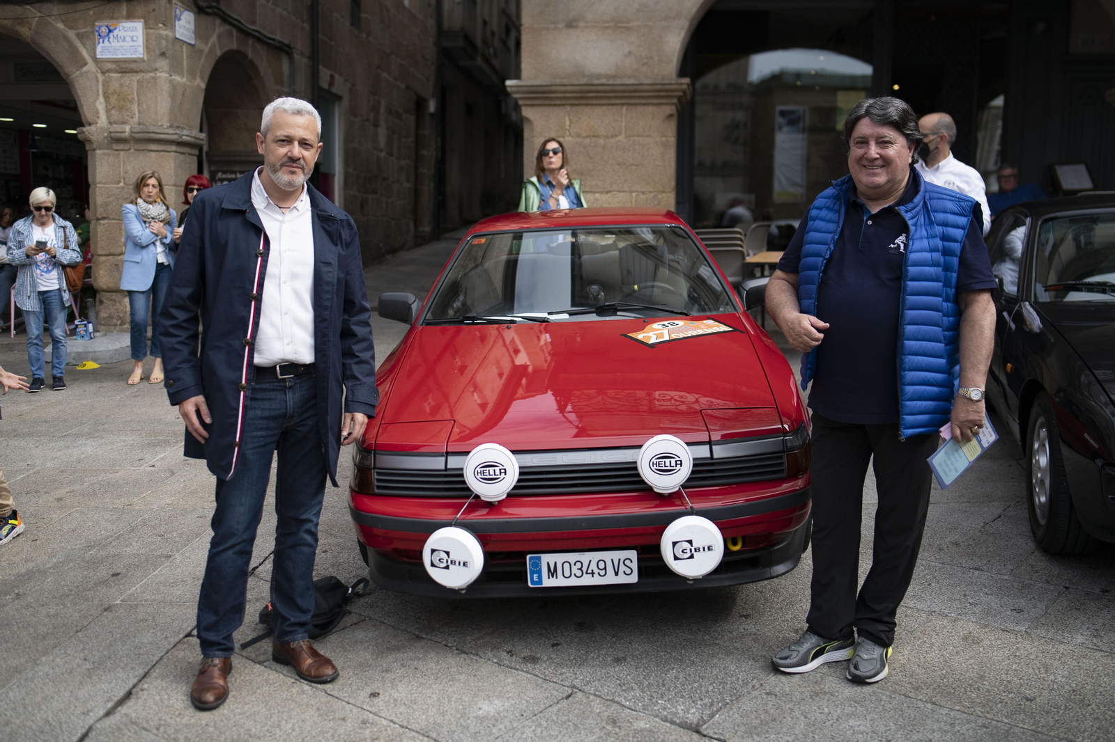 Dos señores posando con un coche antiguo de rally en Ourense