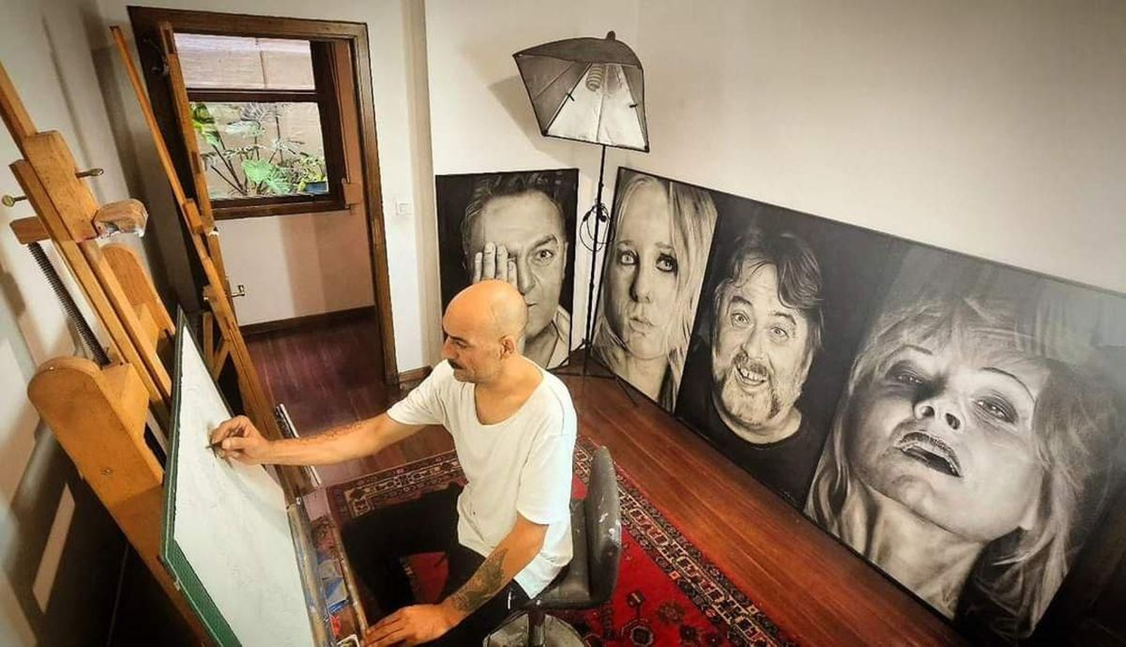 Marcos Puhinger, trabajando en su estudio bajo las “miradas” de los retratos expuestos en Matadero en 2019.