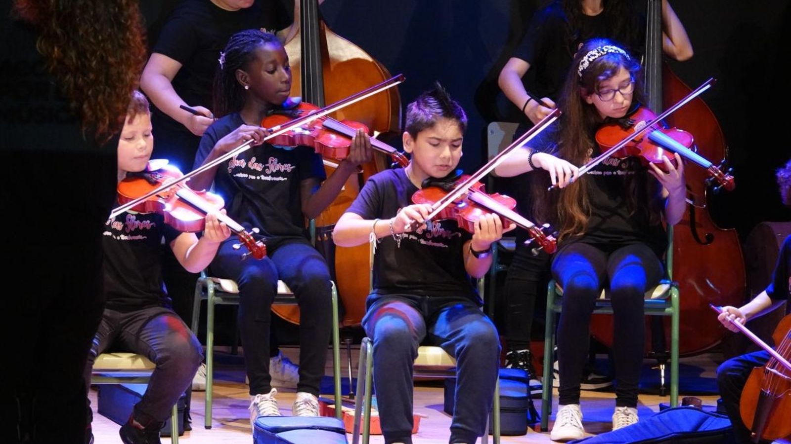 Algunos de los niños músicos tocando los instrumentos, violines y violonchelos.