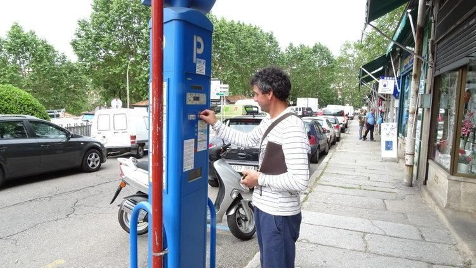 Un conductor retira un tique de un parquímetro de la ciudad.