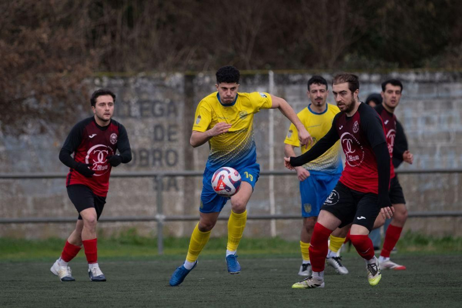 David, jugador del cuadro industrial, intenta marcharse con el balón ante la presencia de Castañer, del Brollón.
