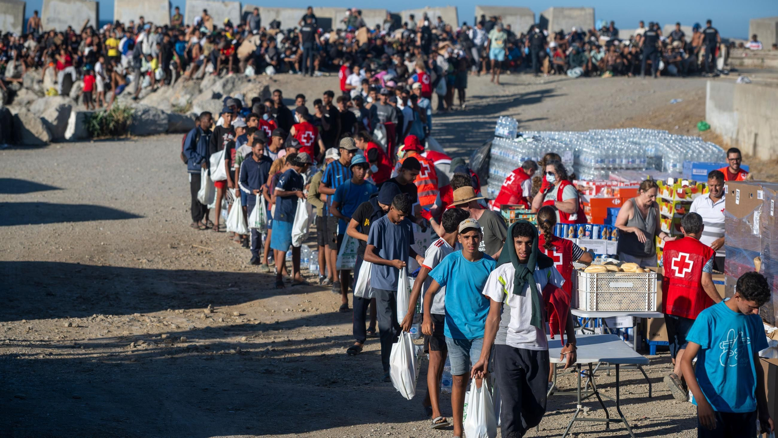 Miembros de la Cruz Roja reparten comida a los inmigrantes en una playa, a 21 de agosto de 2026, en Ceuta (España)