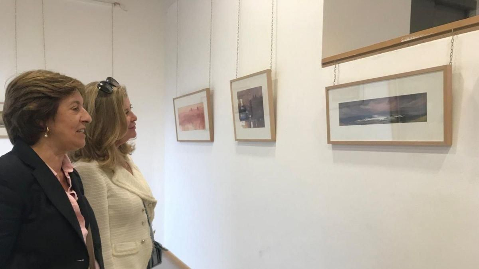 Dos asistentes a la inauguración observando las acuarelas que forman la muestra.