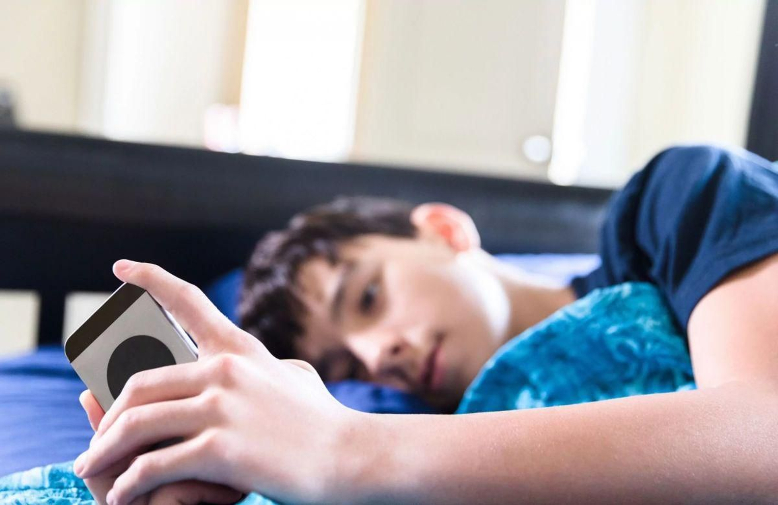 Un adolescente mirando su móvil antes de dormir.