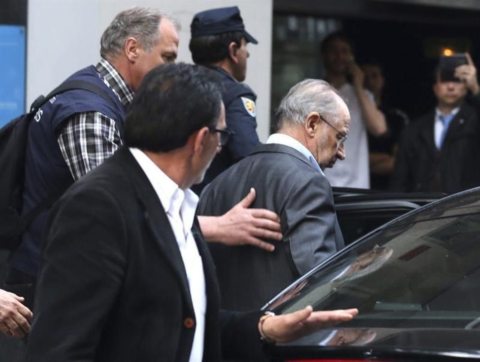 Rodrigo Rato entra en un vehículo tras salir hoy de su domicilio de Madrid escoltado por agentes de Aduanas. (EFE)