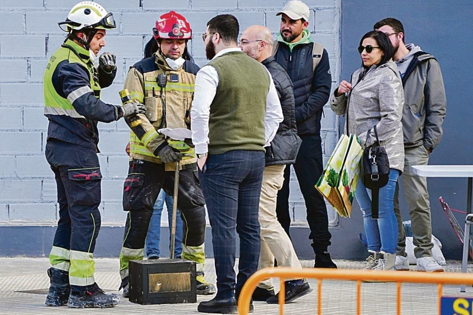 Dos bomberos hablan con algunos de los afectados.