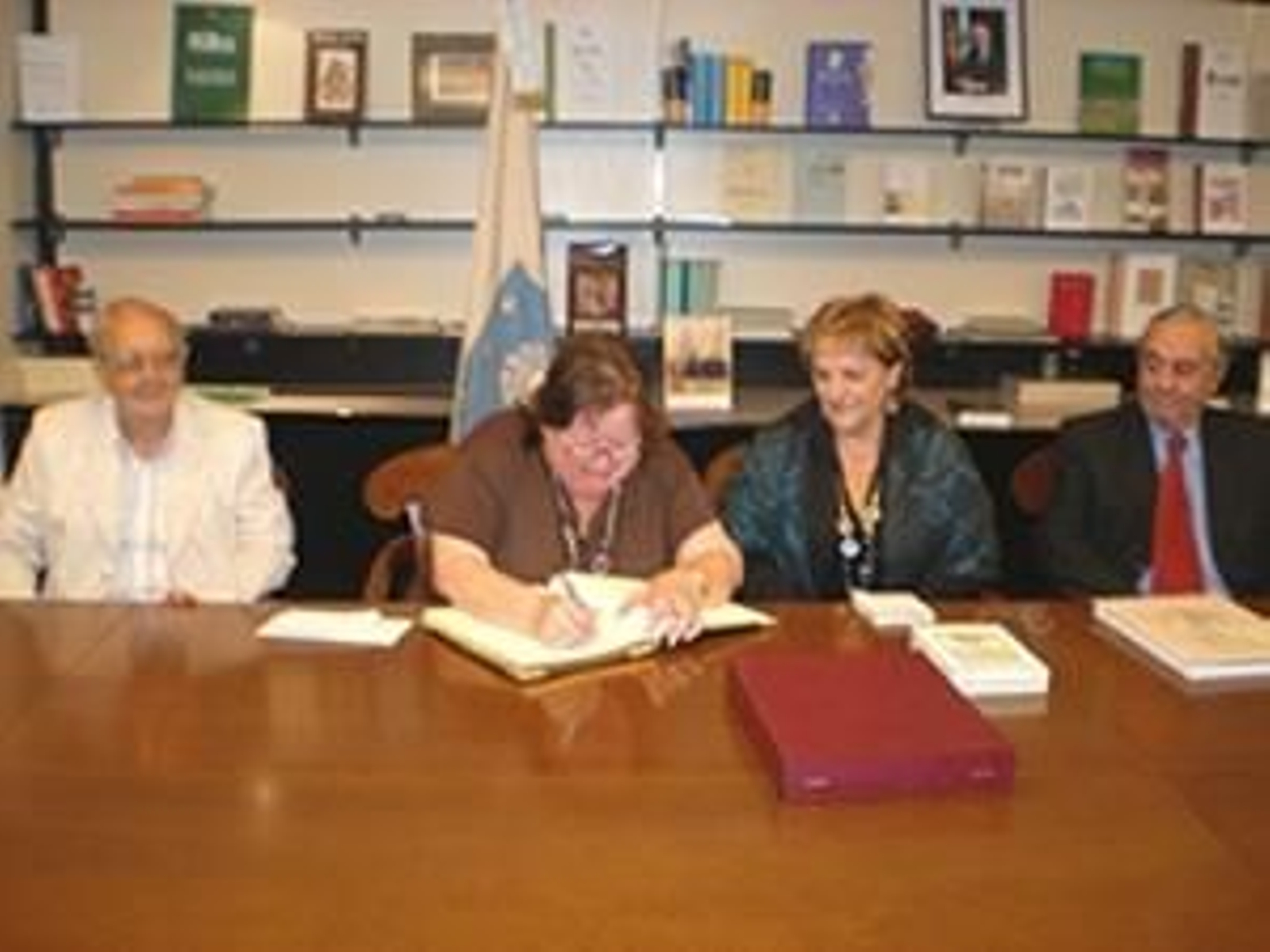 Beatriz Lagoa, presidenta del Centro Betanzos, firma en el libro de honor de la Delegación de la Xunta de Galicia, ante la mirada de María Xosé Porteiro.