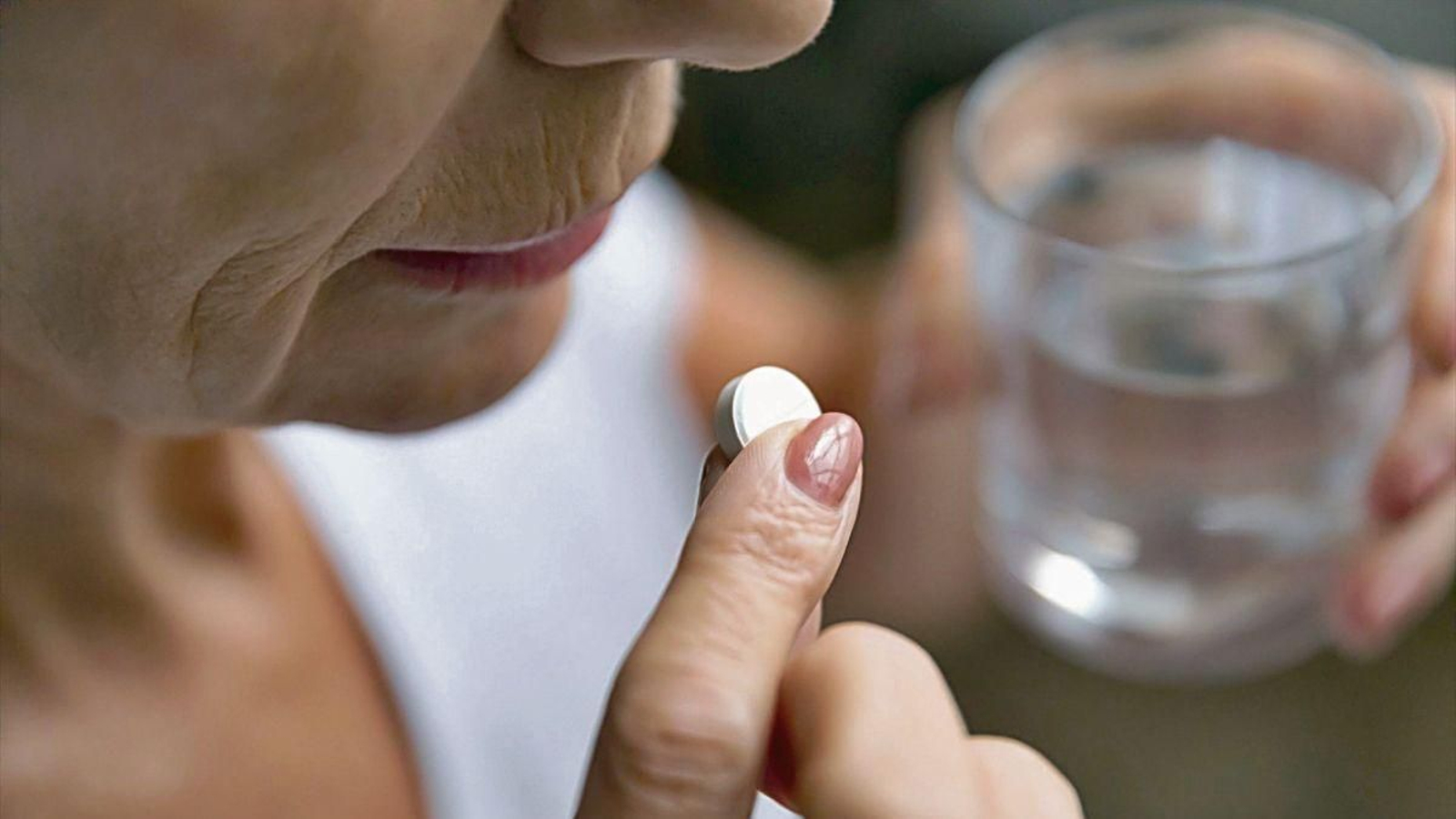 Una mujer toma medicación para la menopausia.