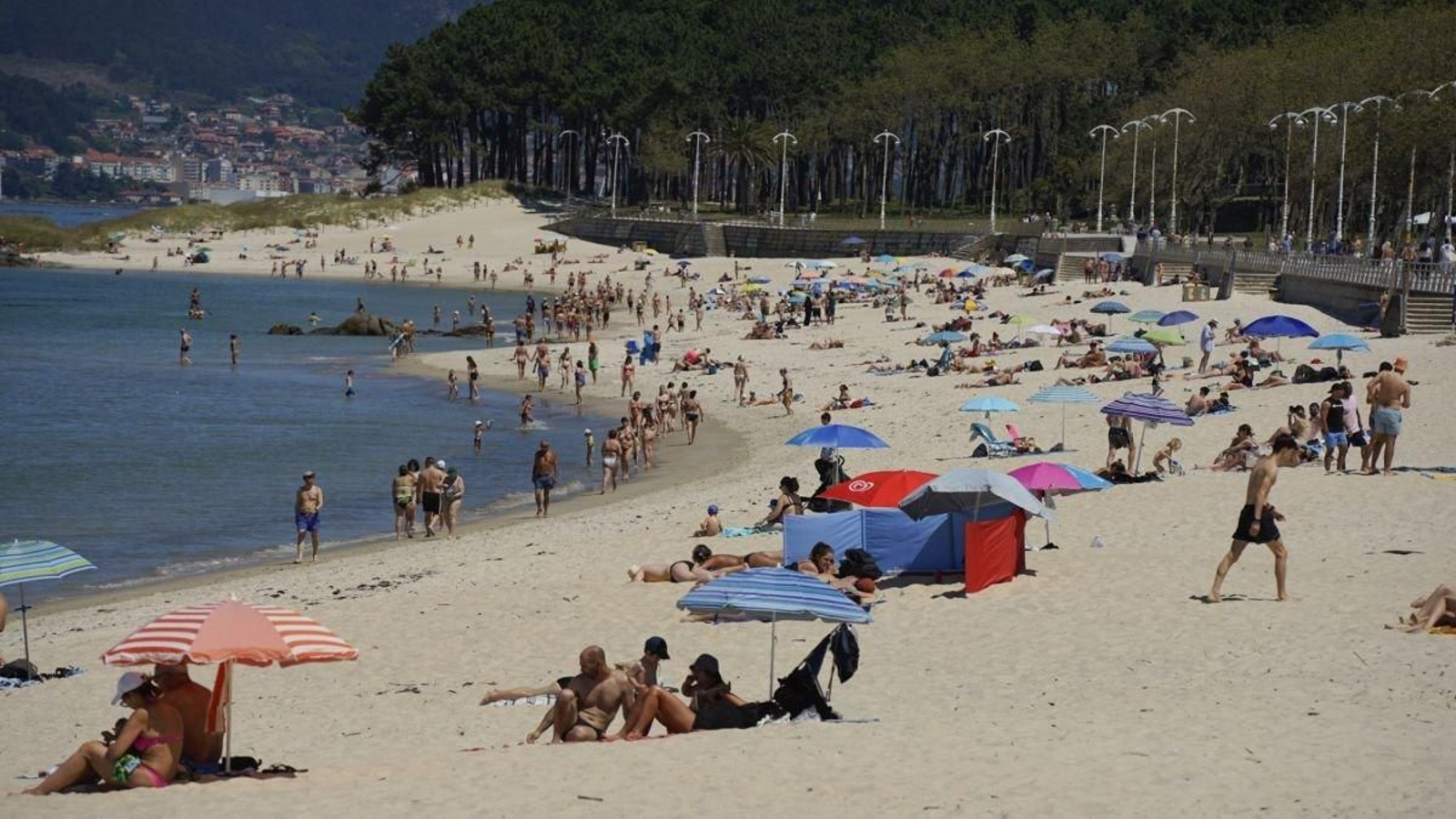 Gente tomando el sol y bañándose en la Playa de Samil.