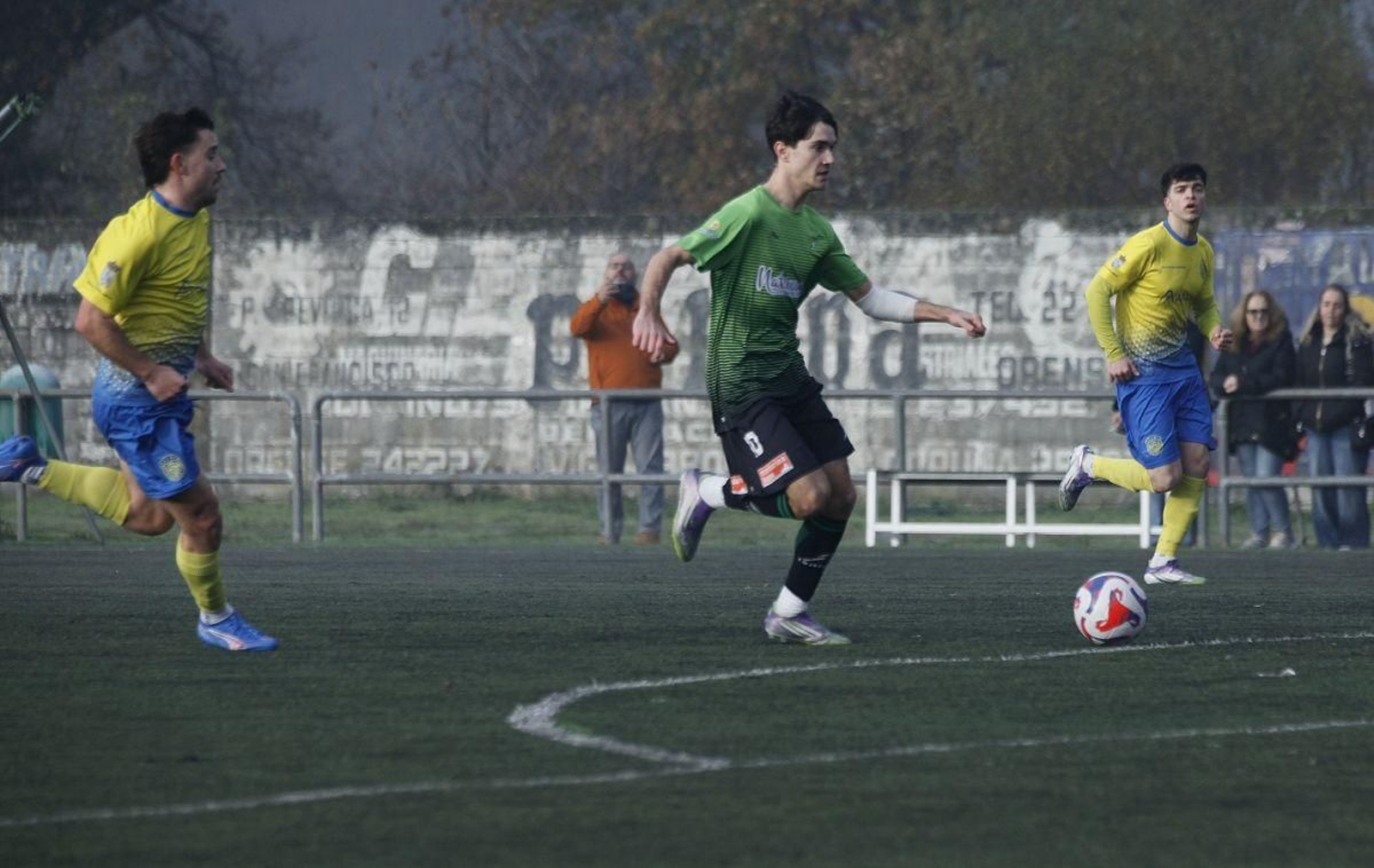 Suances, uno de los destacados en La Purísima, se lleva el balón ante la mirada de un defensa industrial.