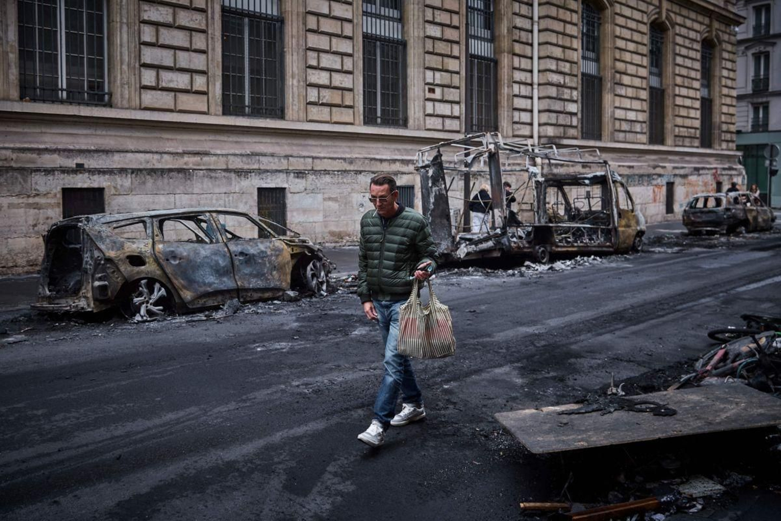 Un hombre pasa junto a vehículos calcinados en París.