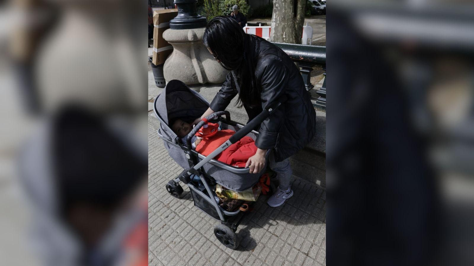 Una mujer arropa a un bebé en la ciudad.
