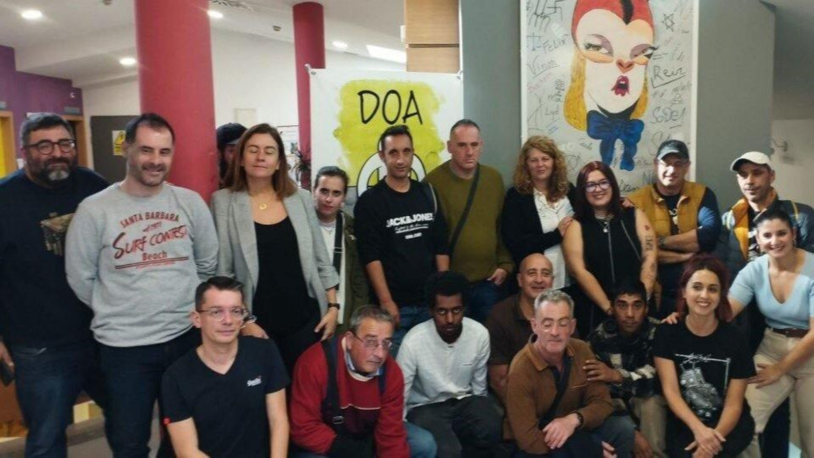 Usuarios y profesonares de DOA con el equipo de gobierno mostrando el cuadro de arte urbano colgado de la pared.