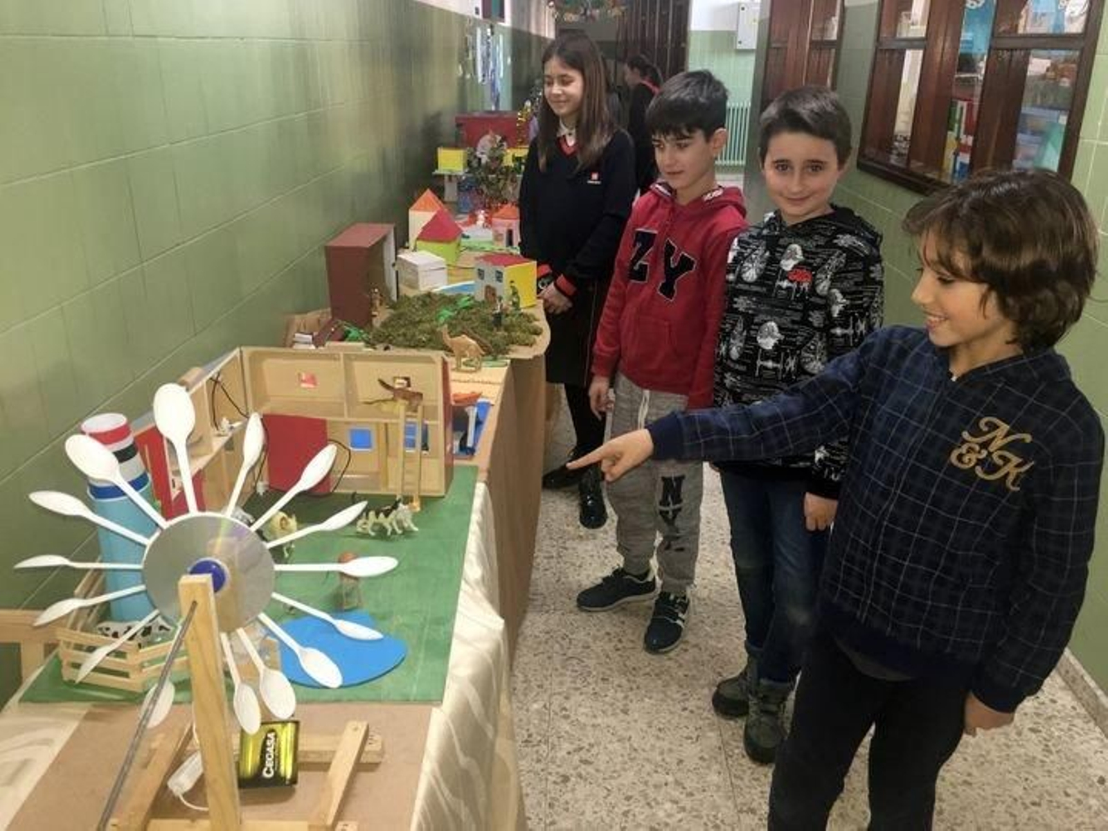 Un alumno muestra su maqueta a dos de sus compañeros.