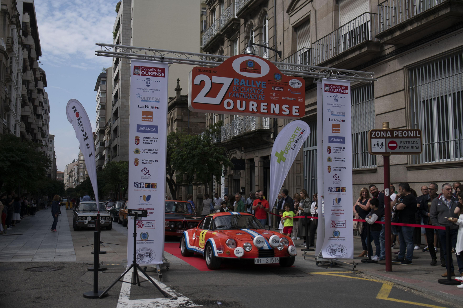 Coche de rally antiguo circulando por Ourense entre un montón de gente