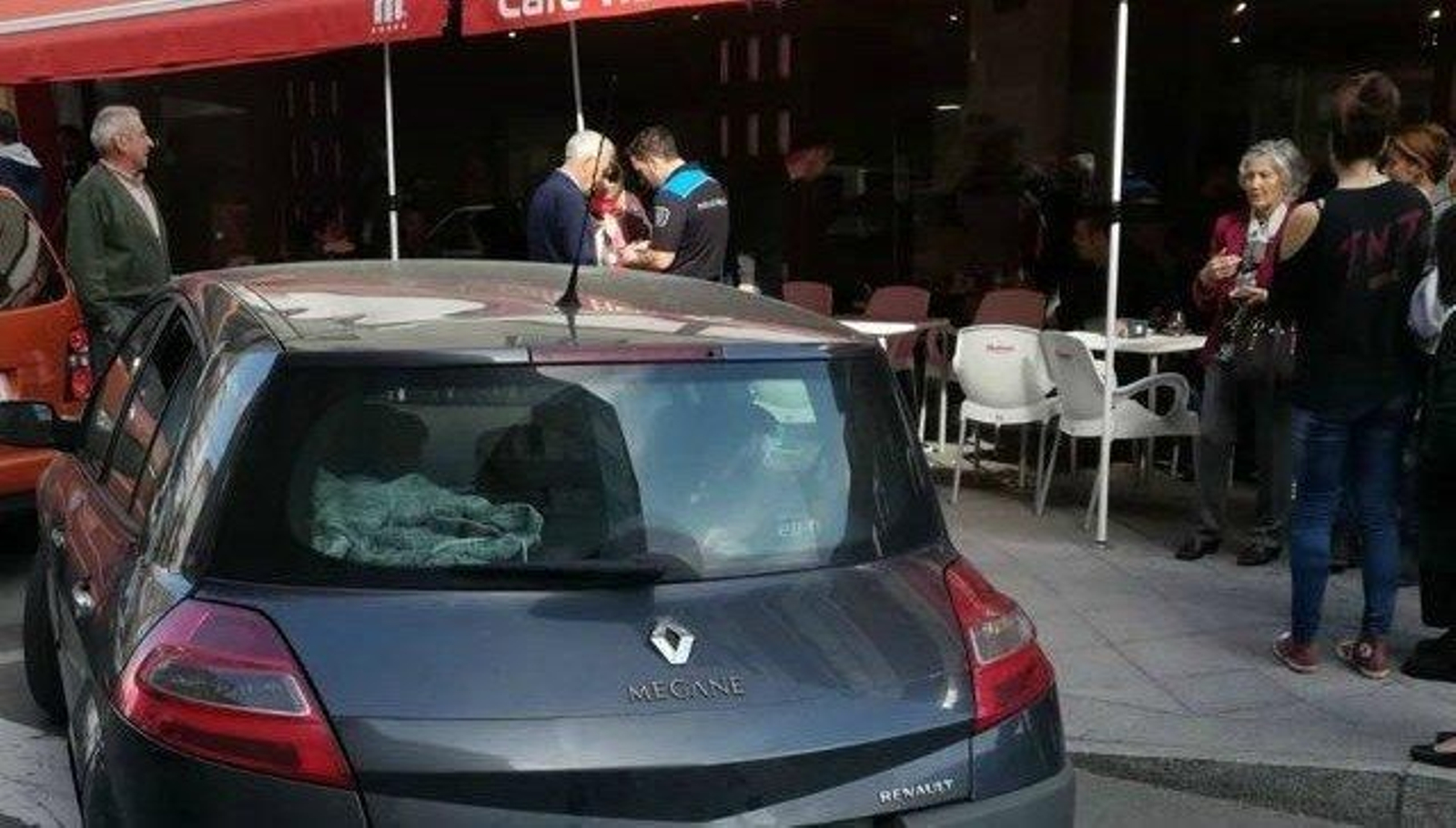 Un policía local dialoga con uno de los testigos de los hechos. En primer término, el coche del policía detenido.