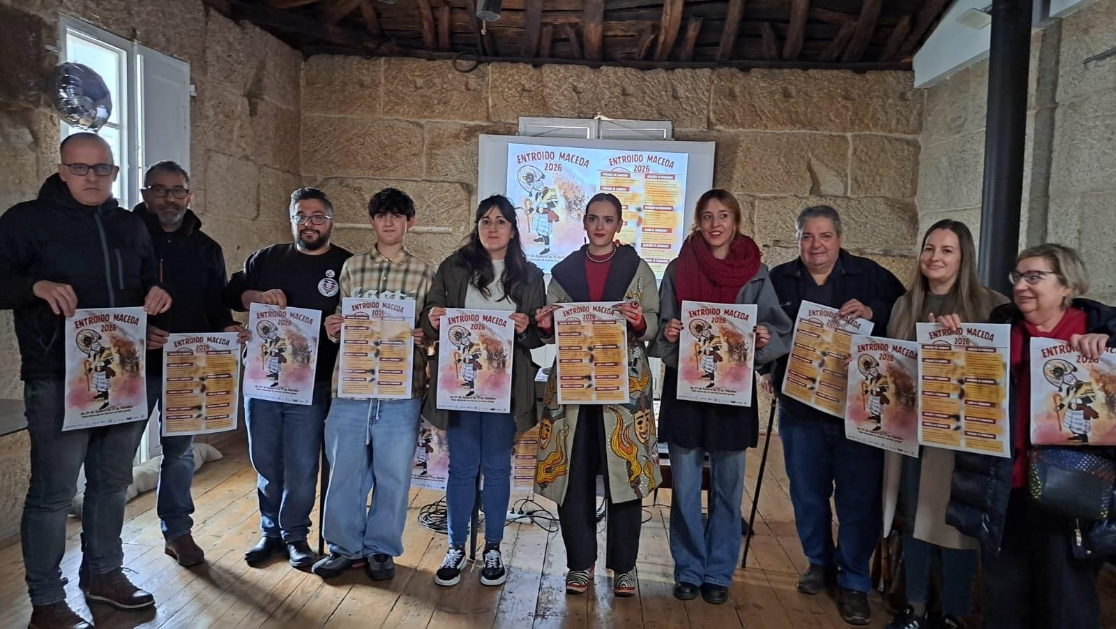 Los participantes en la presentación del programa y el cartel oficial del Entroido de 2026.