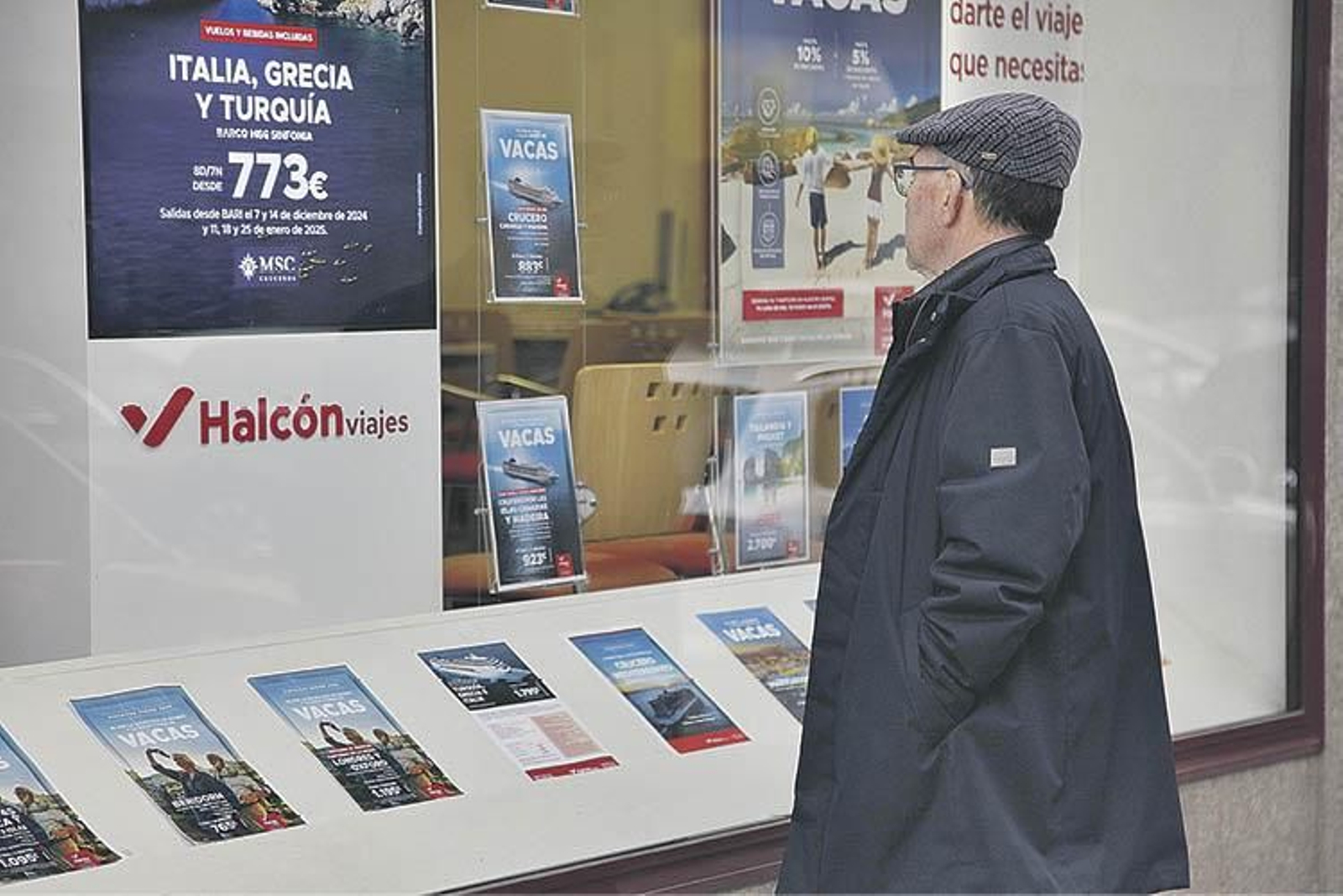 Un hombre obseerva opciones de viaje en un escaparate de una agencia de viajes