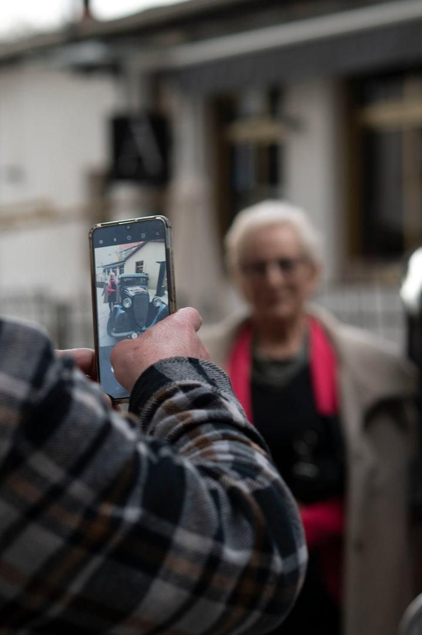 Señora posando para una foto con el coche que patrocina la fiesta.
