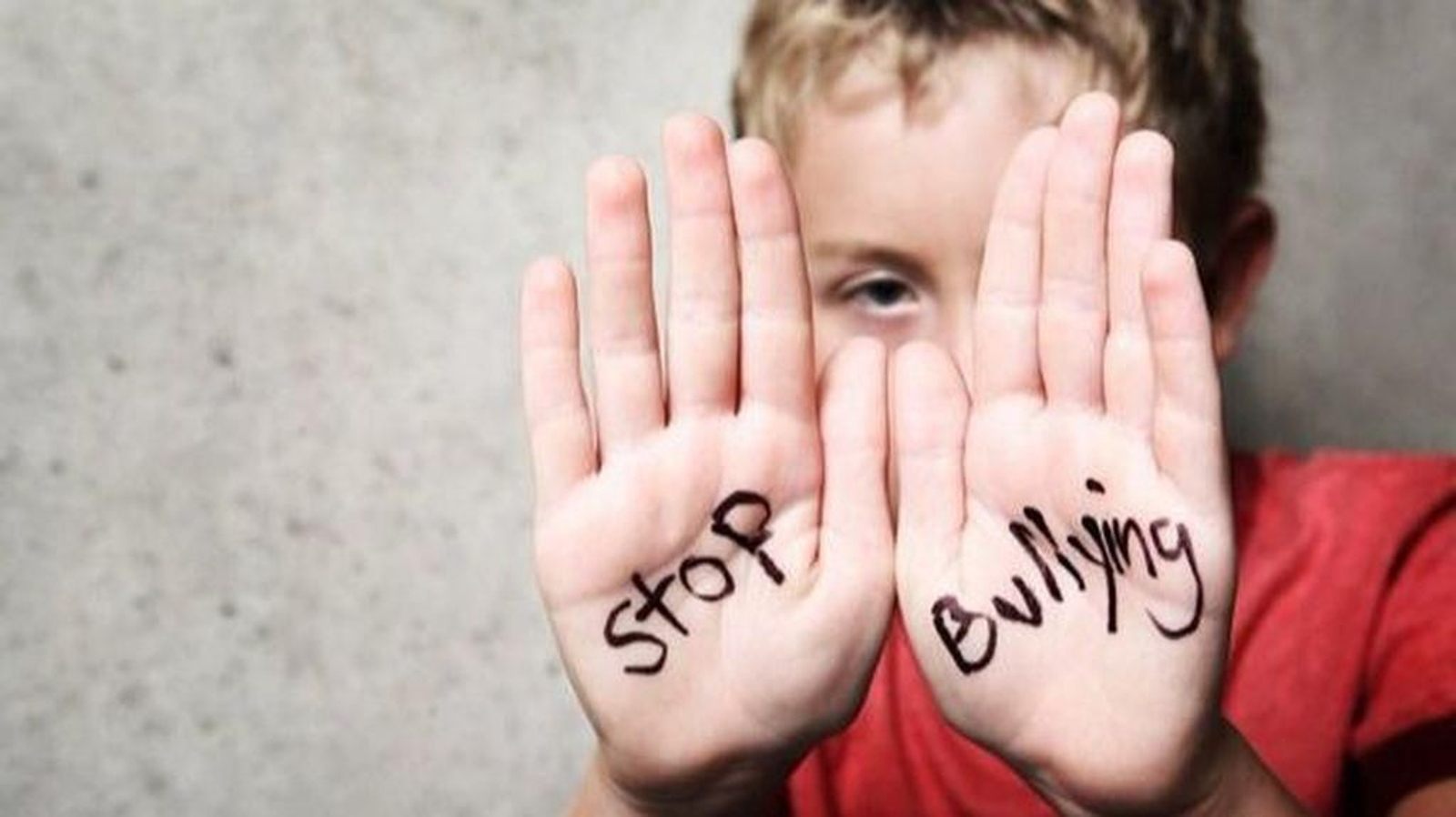 Imagen de un alumno con las palmas de las manos escritas con la frase: "Stop Bullying!" (¡Fin al acoso!).