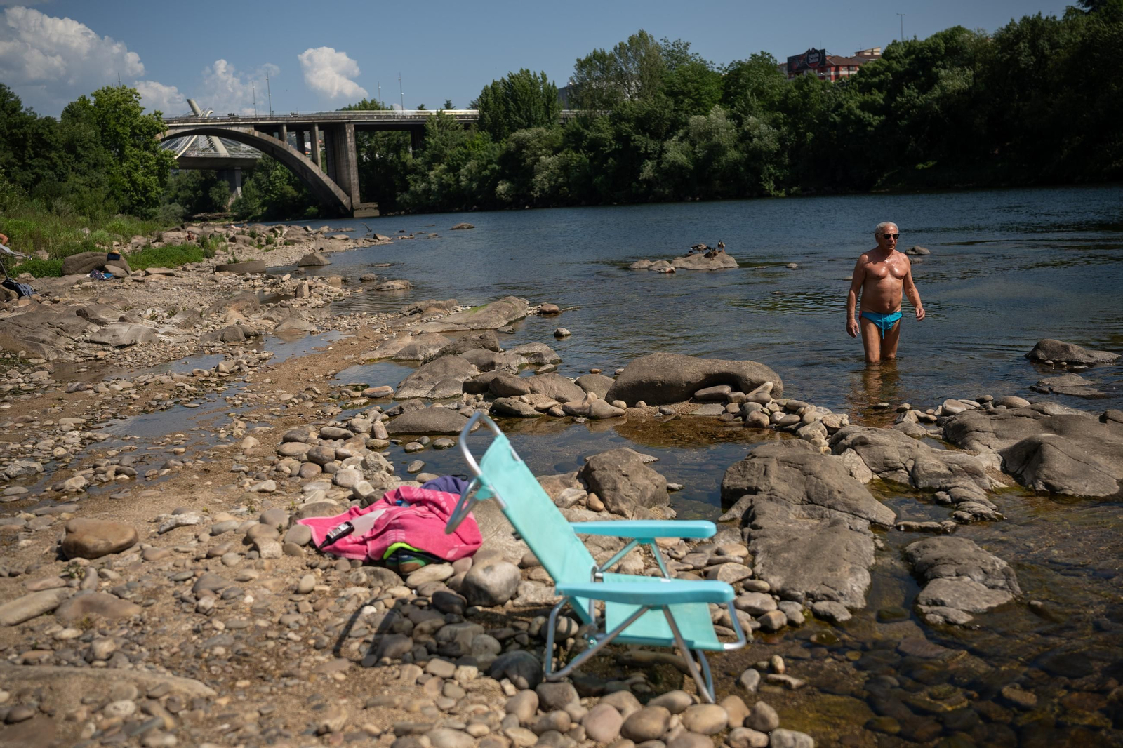 Con sus sillas, los ourensanos se acercan al río para combatir el calor.