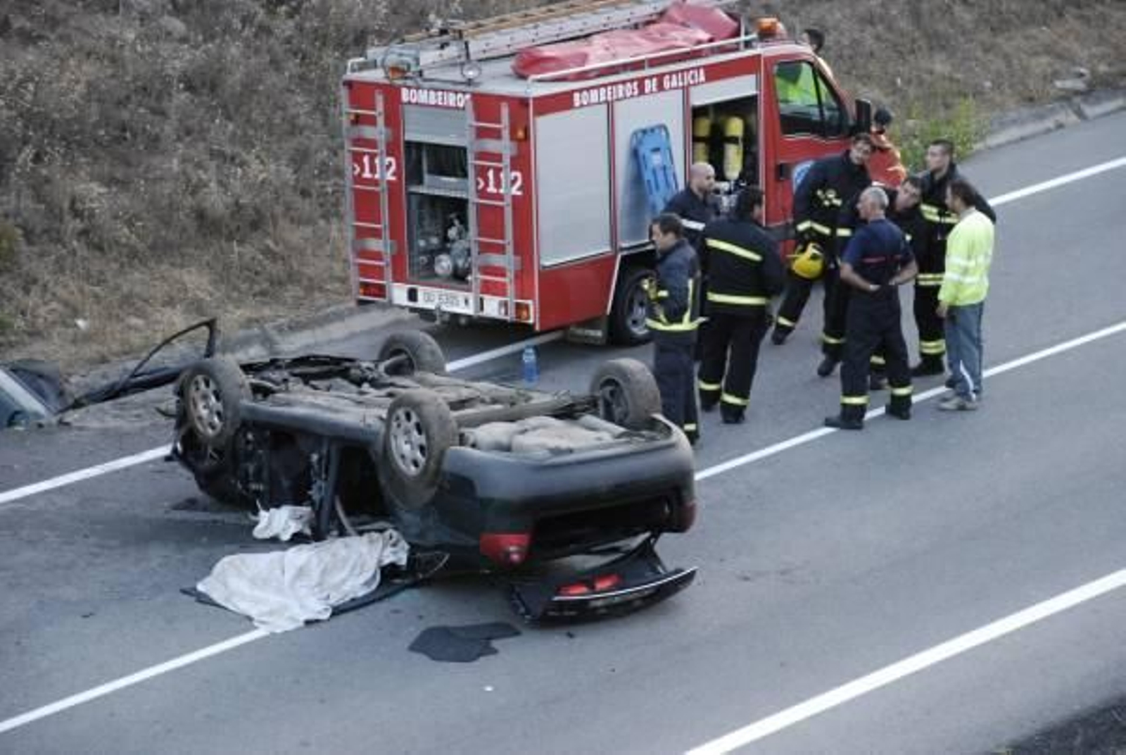 Los bomberos de O Barco ante el vehículo en el que viajaban los seis jóvenes accidentados. Foto: Luís Blanco
