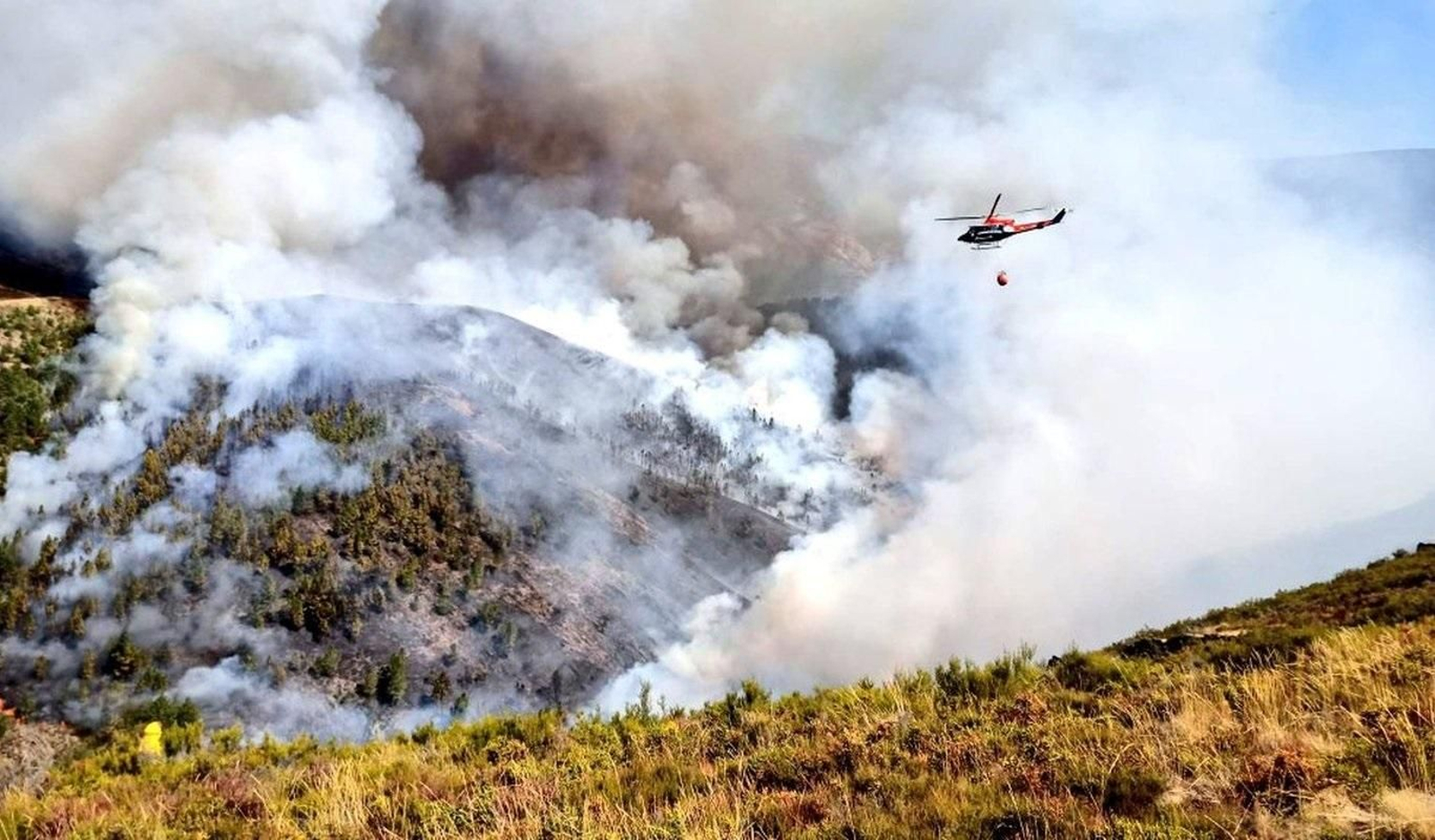 Un helicóptero descarga agua sobre el incendio de Vilar de Barrio.