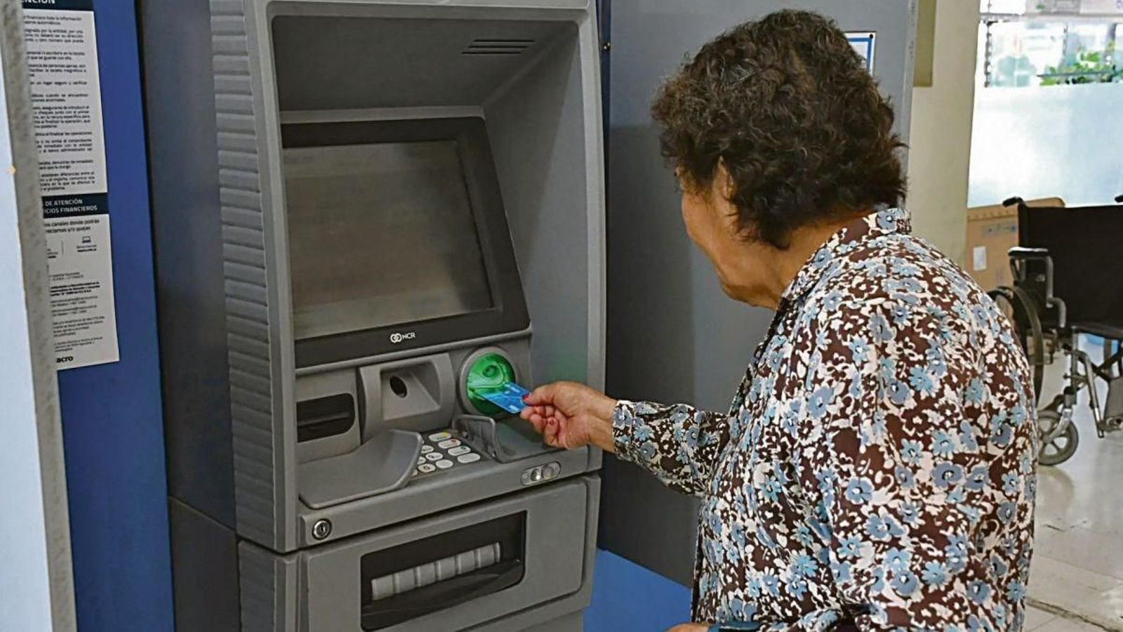 Una mujer introduce su tarjeta en un cajero.
