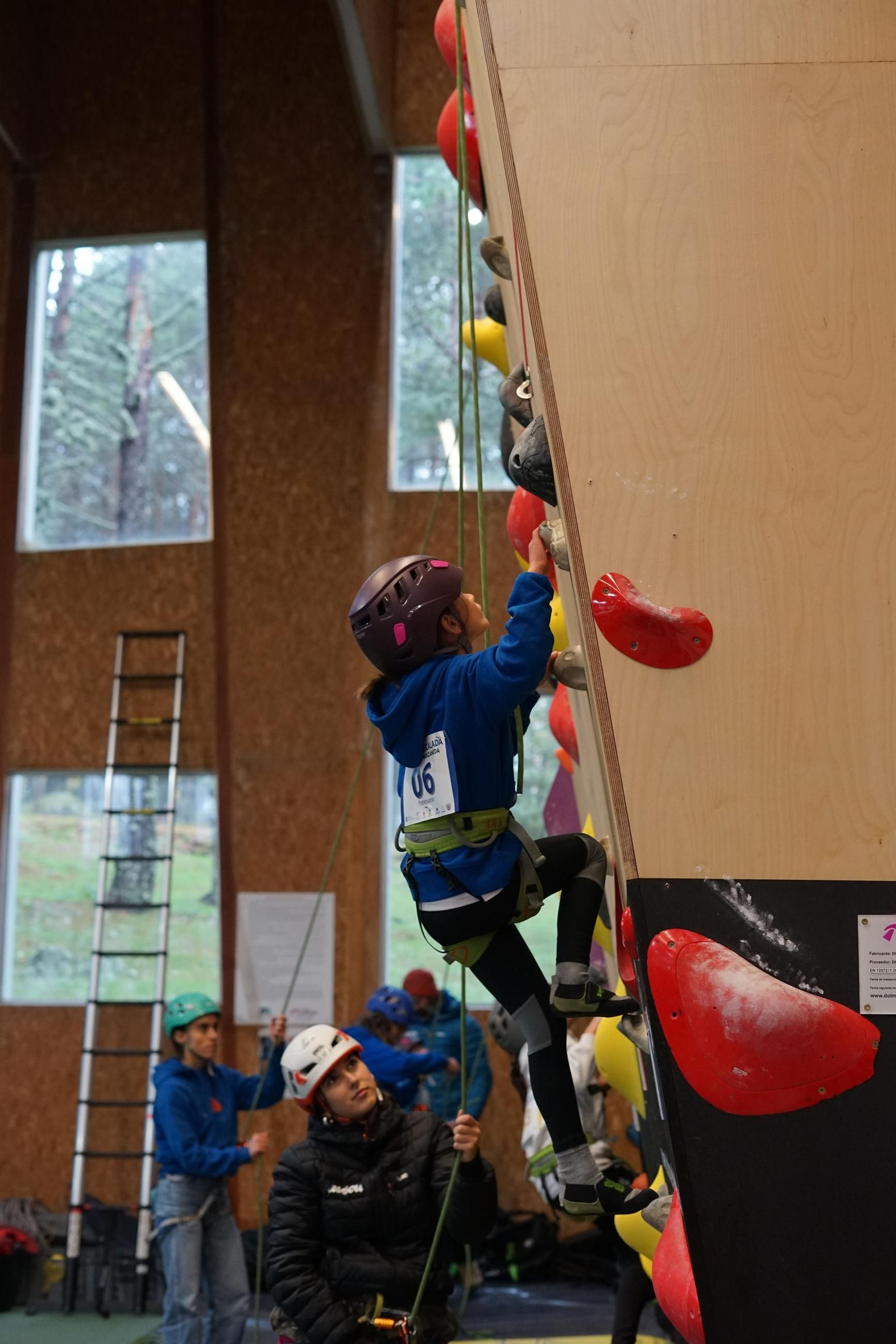 La joven escaladora comienza a subir por el rocodromo.