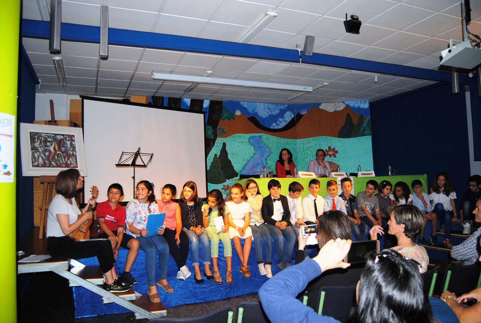 Caíno con su ahijada, la edil Carmen Paredes escucha como suenan sus versos en la voz de los escolares.