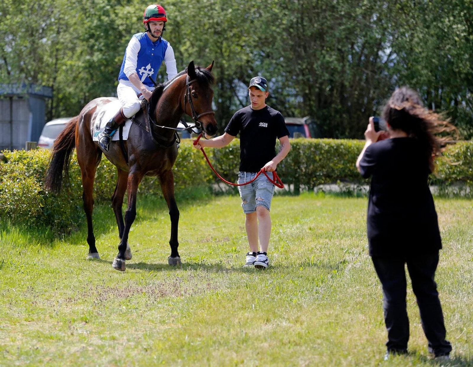 El corredor y el encargado del caballo preparándose para salir.