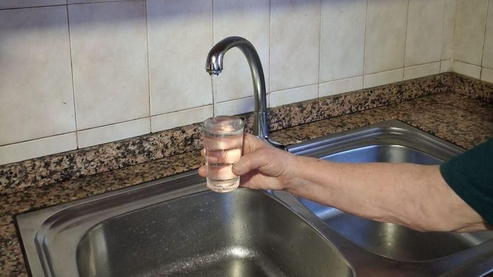 Usuaria que muestra un vaso de agua del grifo, cuya turbidez es imperceptible a la vista.
