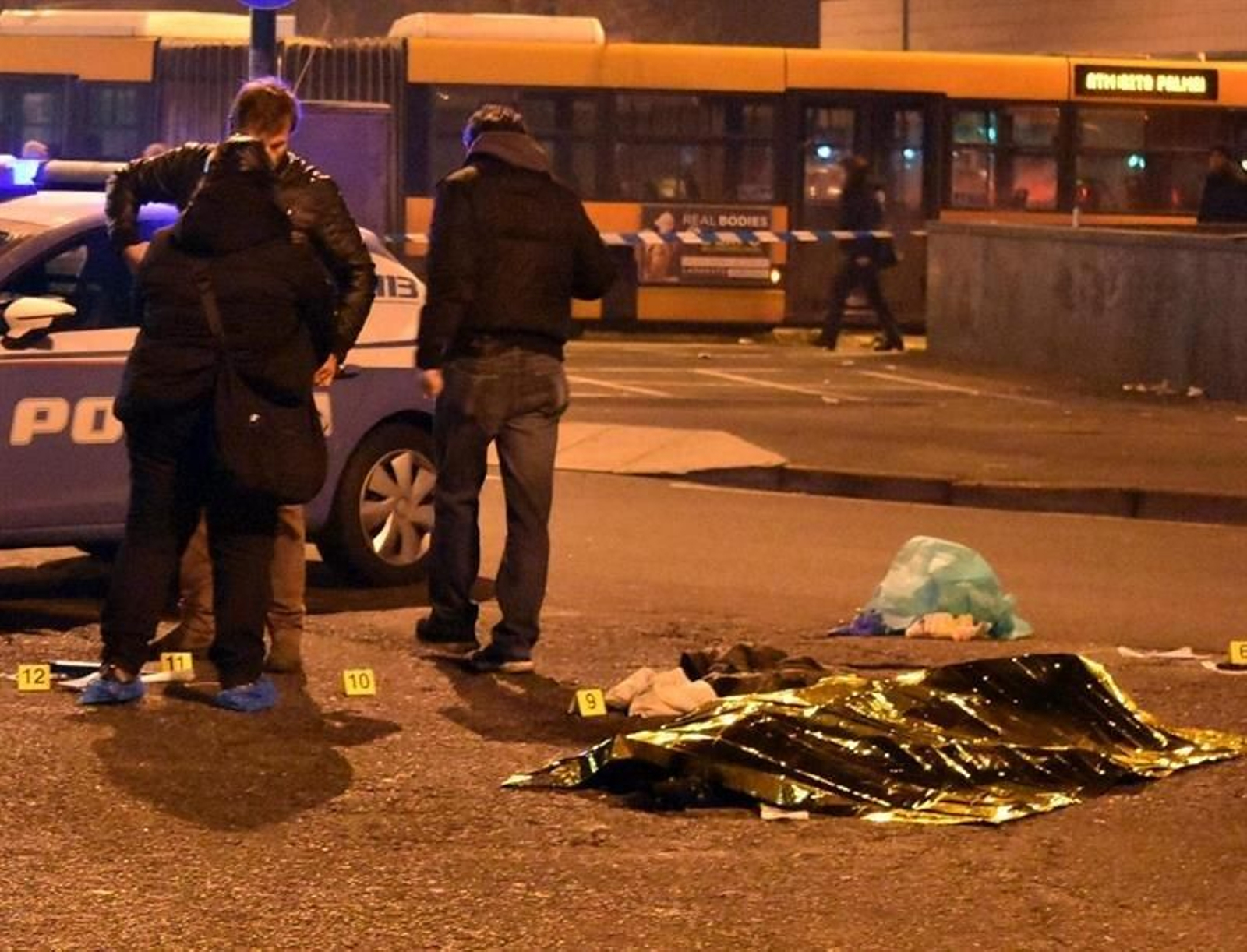 Policías permanecen junto al cuerpo sin vida del tunecino de 24 años sospechoso de cometer el atentado de Berlín, Anis Amri, tras ser abatido en un tiroteo con la Policía italiana en la ciudad de Milán.
